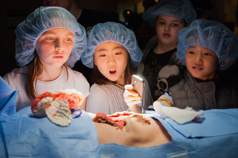 kids in surgical hats watch mock surgery